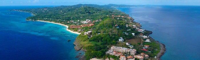 Vue aérienne de l’île de Roatán avec la plage de West Bay, l’eau turquoise et des hôtels à flanc de colline