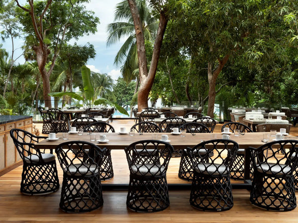 Tropical outdoor restaurant in Roatán with wooden table, wicker chairs and palm trees