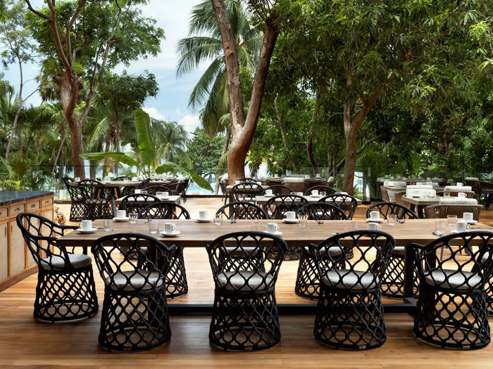 Tropical outdoor restaurant in Roatán with wooden table, wicker chairs and palm trees